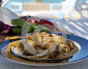 Sicilian pasta dish with traditional busiata pasta and sicilian vegetables, Viola eggplant, tomatoes served ourdoor on terrace