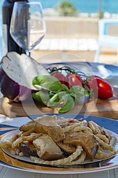 Sicilian pasta dish with traditional busiata pasta and sicilian vegetables, Viola eggplant, tomatoes served ourdoor on terrace