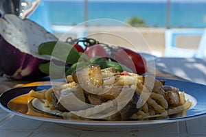 Sicilian pasta dish with traditional busiata pasta and sicilian vegetables, Viola eggplant, tomatoes served ourdoor on terrace