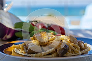 Sicilian pasta dish with traditional busiata pasta and sicilian vegetables, Viola eggplant, tomatoes served ourdoor on terrace