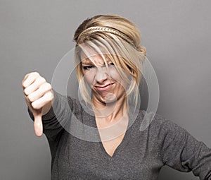 Sick 20s girl expressing repulsion with thumb down and grimace