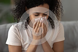 Sick african American woman blowing nose having rhinitis