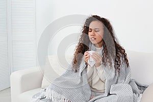 Sick African American woman sneezing at home, space for text