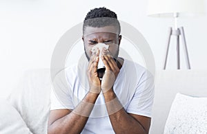 Sick african guy cleaning his snotty nose at home