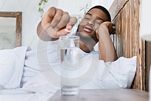 Sick African Guy Putting Pill Into Glass Lying In Bed