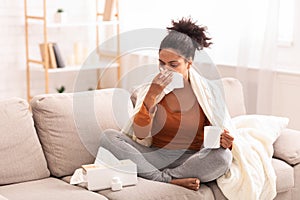 Sick Afro Woman Blowing Nose In Tissue Sitting On Sofa