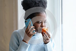 Sick afro woman trying to sense smell of half fresh tangerine orange talking on phone. Covid-19