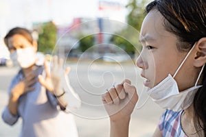 Sick asian child girl with fever and dry cough,woman opened a protective mask while coughing,spreading flu,cold,Covid-19 or