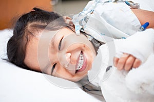 Sick asian child girl is lay down on the bed and smiling