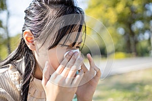 Sick asian child girl sneezing in a tissue blowing her runny nose suffer from cold,female people has flu, rhinitis,seasonal virus