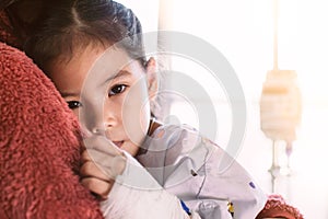 Sick asian child girl who have IV solution hugging her mother