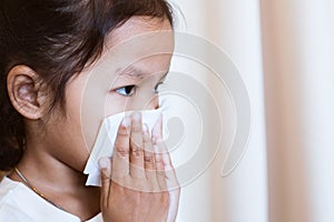 Sick asian child girl wiping and cleaning nose with tissue