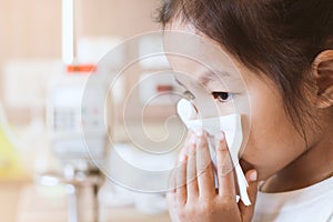 Sick asian child girl wiping and cleaning nose with tissue