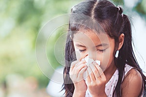 Sick asian child girl wiping and cleaning nose with tissue