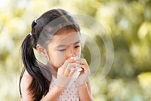 Sick asian child girl wiping and cleaning nose with tissue