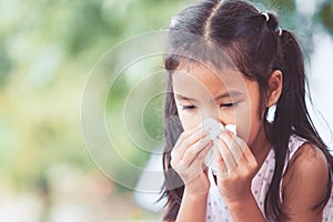 Sick asian child girl wiping and cleaning nose with tissue