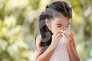 Sick asian child girl wiping and cleaning nose with tissue