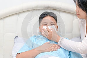 Sick asian child wiping or cleaning nose with tissue