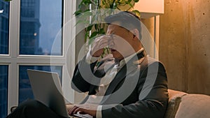 Sick Asian chinese korean male businessman tired exhausted man overworked late job with laptop in evening office