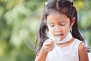 Sick asian girl wear protective mask was taking syrup medicine