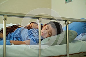 Sick Asian kid boy 2 years old lying sick in hospital bed.