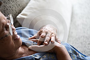 Sick asian old woman lying on sofa and having a pain on heart, heart attack at home. Senior healthcare concept