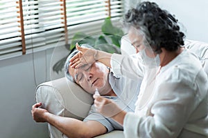 Sick Asian Senior man having flu while his wife check at thermometer