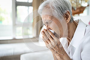 Sick asian senior woman blowing nose with tissue paper while runny nose,sneeze,elderly with sinusitis,sinus virus disease,