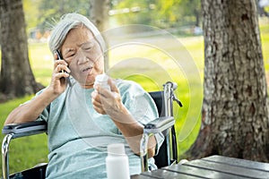 Sick asian senior woman holding bottle of medicine,.calling doctor requesting information,worried female elderly consulting,asking