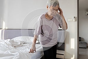 Sick asian senior woman suffering from dizziness sensation of spinning around losing her balance old elderly touching her temple