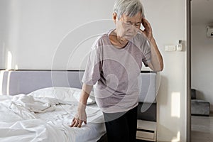 Sick asian senior woman suffering from dizziness sensation of spinning around losing her balance old elderly touching her temple photo