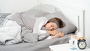 Sick Asian woman with cold sleeping on bed at home with high fever suffering from insomnia