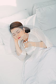 Sick Asian woman with cold sleeping on bed at home with high fever suffering from insomnia