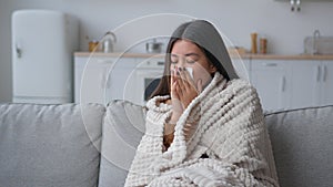 Sick Asian woman covered in blanket sneezing in paper napkin sneeze runny nose feel frozen cold unhealthy korean girl