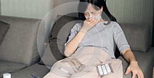 Sick asian woman with face mask having cough on sofa bed at home