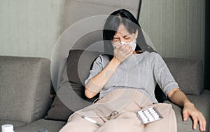 Sick asian woman with face mask having cough on sofa bed at home