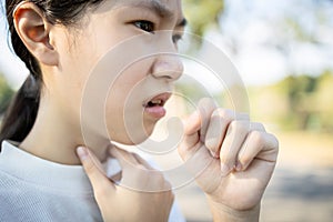 Sick asian woman has a chronic cough with tonsillitis,ill child girl touch the neck with fever,acute cough,sore throat pain photo