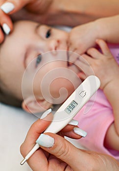 Sick baby being checked for fever.