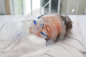 Sick baby boy applying inhale medication by inhalation mask to cure Respiratory Syncytial Virus RSV on patient bed at hospital