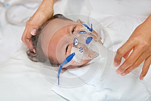 Sick baby boy applying inhale medication by inhalation mask to cure Respiratory Syncytial Virus RSV on patient bed at hospital