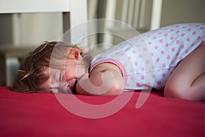 Sick baby girl lying in bed and crying
