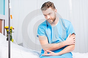 Sick bearded man sitting on hospital bed