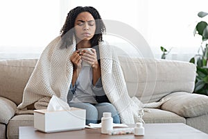 Sick Black Woman Feeling Unwell At Home, Drinking Tea On Couch