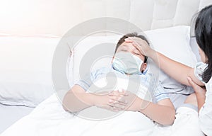 Sick boy with hygienic mask laying on bed