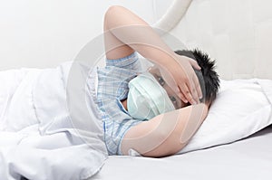 Sick boy with hygienic mask lie down on bed