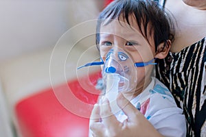 Sick boy inhalation therapy by the mask of inhaler. Baby has asthma and need nebulizations photo