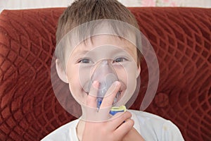 Sick boy in nebulizer mask making inhalation, respiratory procedure by pneumonia or cough
