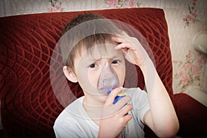 Sick boy in nebulizer mask making inhalation, respiratory procedure by pneumonia or cough for child