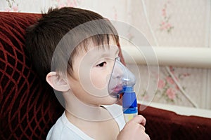 Sick boy in nebulizer mask making inhalation, respiratory procedure by pneumonia or cough for child, inhaler