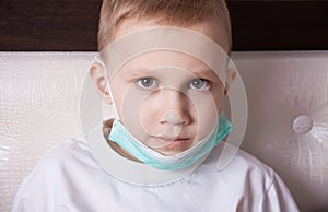 Sick boy sitting in bed in medical mask and doesn t feel well
